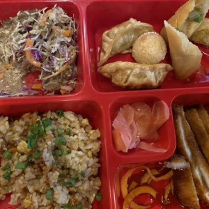 Box con Yakimeshi, gyosas, pollo crispy, spring rolls y ensalada con repollo y zanahorias
