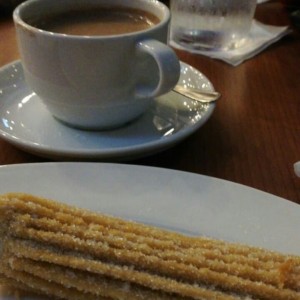 Churro relleno de manjar y chocolate caliente.