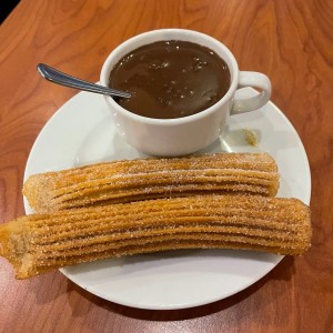 Churro relleno de manzana y canela y taza de chocolate a la espanola