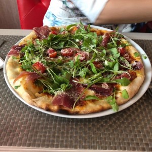 Pizza con jamon serrano, rugula y tomate cherry