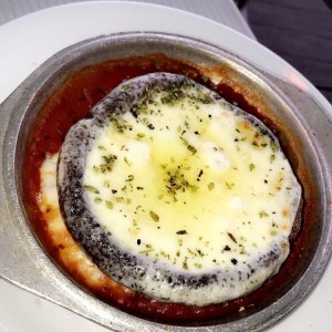 Portobelo relleno de queso provolone sobre cama de salsa de tomate