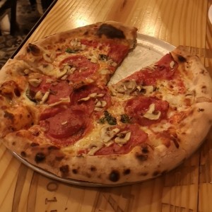 Pizza de pepperoni con hongos y albahaca