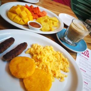 salchichas y huevos revueltos con tortilla, capuchino y frutas