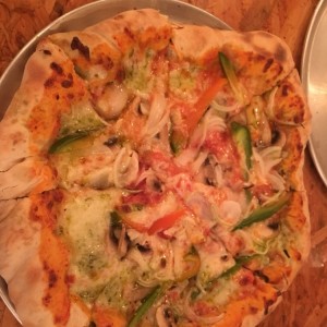 pizza de vegetales con queso y pesto en el borde? 