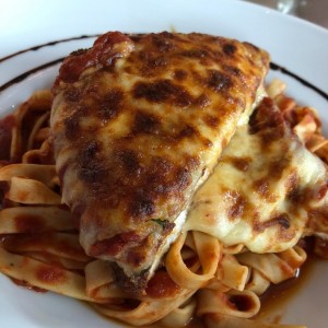 Milanesa de pollo gratinada con fetuchini en salsa pomodoro.