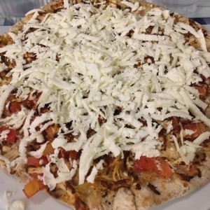 pizza de pollo con tomates en cuadritos con queso feta al entrar y al salir del horno.