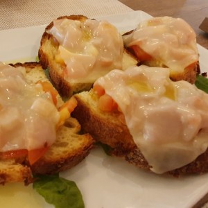 Pan de la casa con trozos de tomate y queso gratinado.