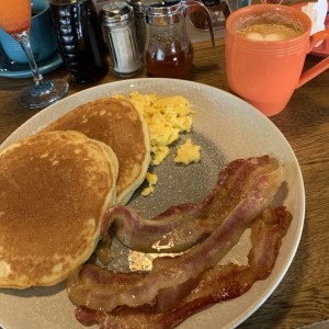 Desayuno de pancakes, bacon y huevo revuelto