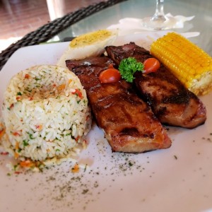 Orden de costillas de cerdo, arroz Pencas, mazorca y pan con ajo